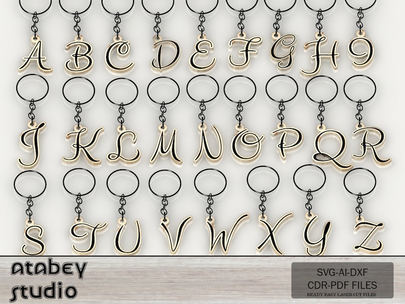 May include: A collection of gold-colored alphabet keychains, each letter suspended from a black chain and keyring. The letters are in a cursive font. The image also includes the text "Atabey studio" and "SVG-AI-DXF CDR-PDF FILES READY EASY LASER CUT FILES".