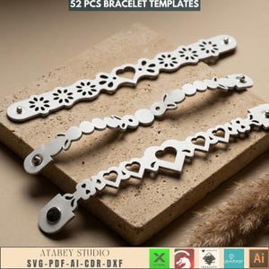 May include: Three silver bracelet templates with various cut-out designs, including hearts, flowers, and circles. The bracelets are displayed on a textured, light brown surface. The text "52 PCS BRACELET TEMPLATES" is at the top.