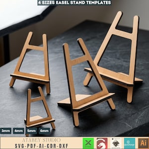 May include: Four wooden easel stand templates in varying sizes. The stands are made of light-colored wood with dark edges. The image includes text that reads "4 SIZES EASEL STAND TEMPLATES" and "ATABEY STUDIO SVG-PDF-AI-CDR-DXF".