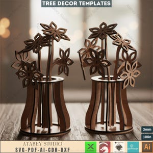 Puede incluir: Dos plantillas de jarrones de flores de madera con diseños florales cortados con láser. Los jarrones son marrones y tienen una construcción en capas. La imagen incluye el texto "TREE DECOR TEMPLATES" y "ATABEY STUDIO SVG-PDF-AI-CDR-DXF".