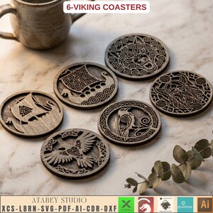 May include: Six circular wooden coasters featuring intricate laser-cut designs of Viking-themed imagery, including longships, a raven, a wolf, and a bearded figure. The text 6-VIKING COASTERS is visible at the top of the image.