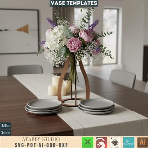 May include: A dining table set with a floral arrangement in a wooden vase. The arrangement includes white, pink, and purple flowers. Two stacks of grey plates are on the table runner. The text "VASE TEMPLATES" is at the top.