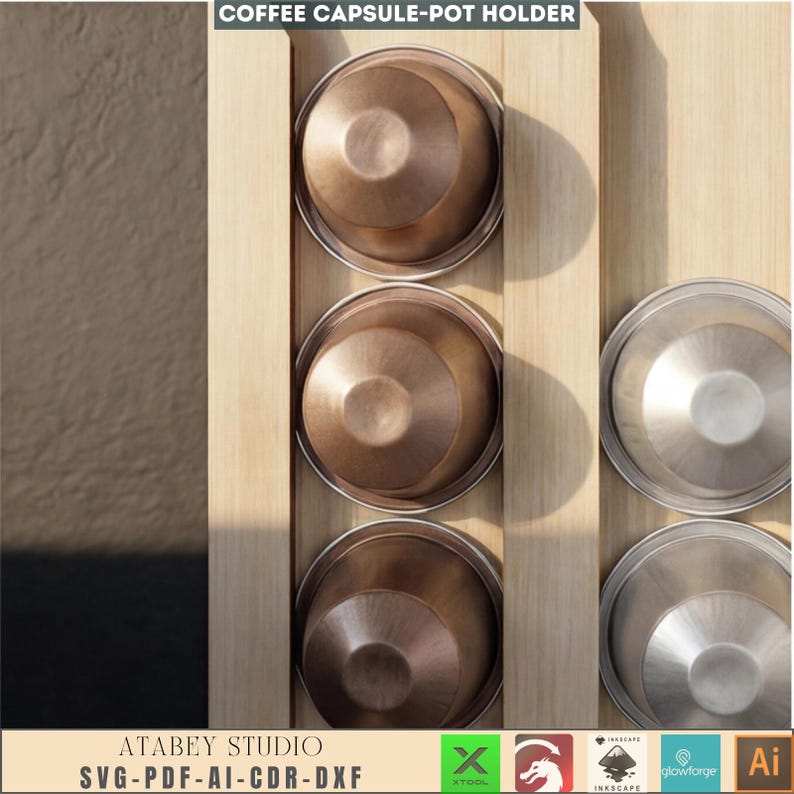 Puede incluir: Un portac&aacute;psulas de caf&eacute; de madera con tres c&aacute;psulas de caf&eacute; de color bronce y tres tapas de color plateado. El soporte es de madera clara. El texto "COFFEE CAPSULE-POT HOLDER" est&aacute; en la parte superior. El texto "ATABEY STUDIO SVG-PDF-AI-CDR-DXF" est&aacute; en la parte inferior.