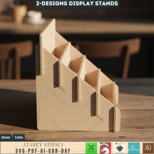 Puede incluir: Un expositor de madera de color claro con m&uacute;ltiples estantes escalonados. El expositor est&aacute; hecho de madera de color claro y tiene el texto "2-DESIGNS DISPLAY STANDS" en la parte superior. El expositor tiene 6 mm de grosor y el logotipo de Atabey Studio.