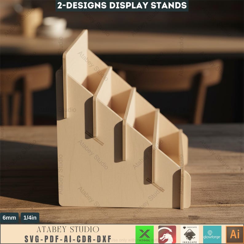 Puede incluir: Un expositor de madera de color claro con m&uacute;ltiples estantes escalonados. El expositor est&aacute; hecho de madera de color claro y tiene el texto "2-DESIGNS DISPLAY STANDS" en la parte superior. El expositor tiene 6 mm de grosor y el logotipo de Atabey Studio.