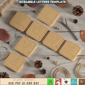 May include: Wooden Scrabble tiles spelling "LOVE" arranged on a light wood surface. Each tile features a letter and a point value. The image includes the text "SCRABBLE LETTERS TEMPLATE" and "ATABEY STUDIO SVG-PDF-AI-CDR-DXF". Decorative elements like pinecones and leaves surround the tiles.