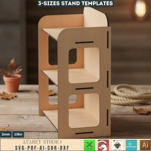 May include: A three-tiered wooden stand with a light brown finish. The stand has a rectangular shape with square cutouts and black accents. The text "3-SIZES STAND TEMPLATES" and "ATABEY STUDIO SVG-PDF-AI-CDR-DXF" are visible.