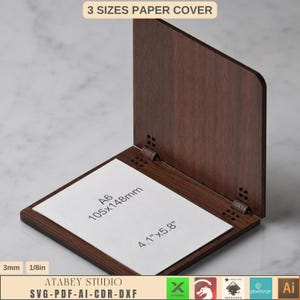 Könnte beinhalten: Ein dunkelbrauner Papierumschlag aus Holz mit Klappdesign. Der Umschlag zeigt eine weiße Einlage mit der Beschriftung A6, 105x148mm und 4,1 Zoll mal 5,8 Zoll. Der Text 3 SIZES PAPER COVER, 3mm, 1/8in und ATABEY STUDIO SVG-PDF-AI-CDR-DXF ist sichtbar.