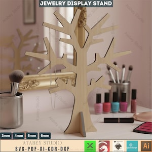 May include: A wooden jewelry display stand in the shape of a tree. The stand has multiple branches for hanging necklaces and other jewelry. The text "JEWELRY DISPLAY STAND" is at the top. The stand is on a white surface with makeup and brushes.