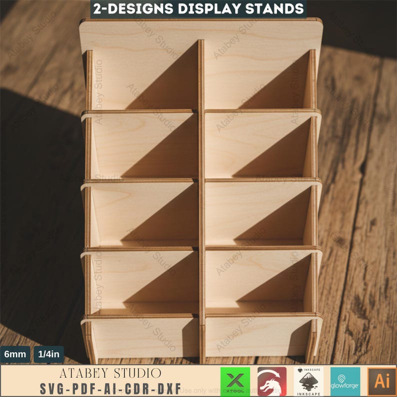 Puede incluir: Un expositor de madera con m&uacute;ltiples compartimentos. El expositor est&aacute; hecho de madera de color claro y presenta un dise&ntilde;o en niveles con varios estantes. El texto "2-DESIGNS DISPLAY STANDS" est&aacute; en la parte superior. El expositor tiene 6 mm (1/4 pulg) de grosor y tiene el texto "ATABEY STUDIO SVG-PDF-AI-CDR-DXF".