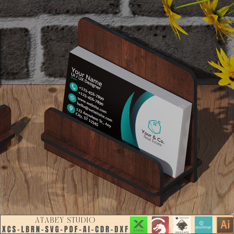 May include: A wooden business card holder with a black business card inside. The card has a teal and black design with the text "Your Name UI/UX Designer" and "Your & Co. Real Estate".