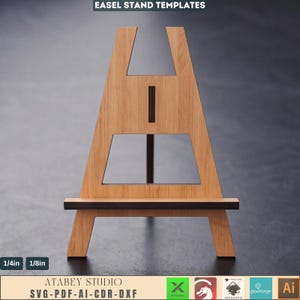 May include: Wooden easel stand template with a light brown finish. The easel has a rectangular base and a frame with a central support. The text "EASEL STAND TEMPLATES" is at the top. The bottom of the image has the text "ATABEY STUDIO SVG-PDF-AI-CDR-DXF".