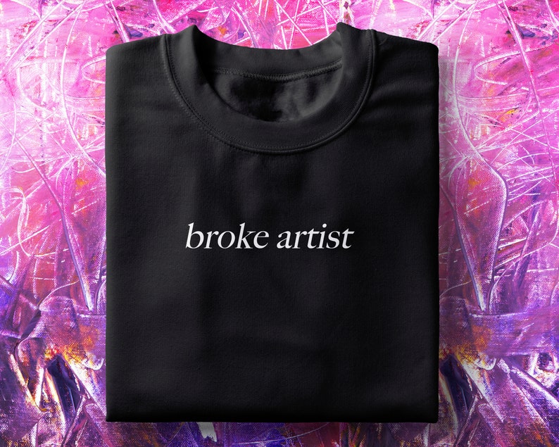 Puede incluir: Camiseta negra con el texto "broke artist" impreso en blanco en la parte delantera.