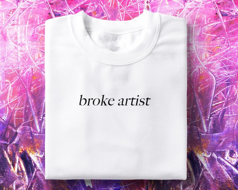 Puede incluir: Sudadera blanca de cuello redondo con el texto "broke artist" impreso en negro en la parte delantera.