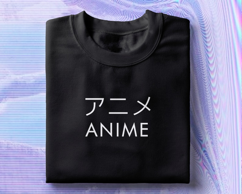Op de afbeelding: Zwart T-shirt met witte tekst die "アニメ ANIME" zegt.