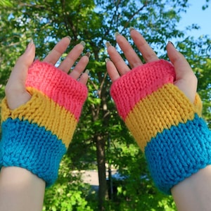 May include: A pair of fingerless gloves knitted in pink, yellow, and blue stripes. The gloves are made with a soft yarn and have a comfortable fit.