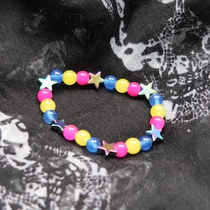 May include: A colorful beaded bracelet with alternating blue, yellow, and pink beads. Each bead has a silver star charm.