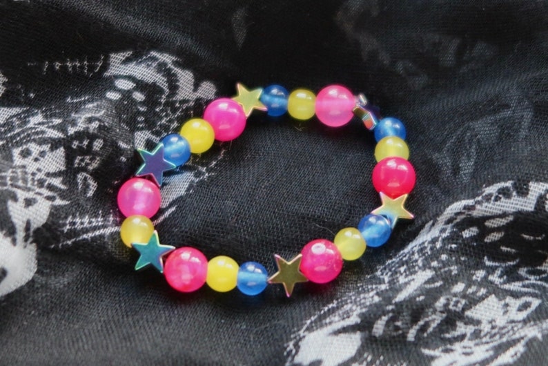 May include: A colorful beaded bracelet with pink, yellow, and blue beads and silver star charms.