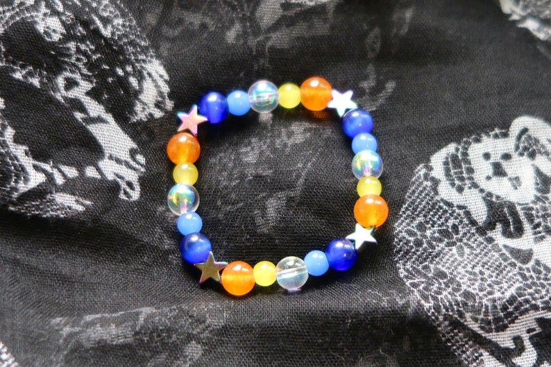 Aroace pride flag star beaded gemstone bracelet. The beads are the aroace flag colors (orange, yellow, white, blues) and holographic stars.