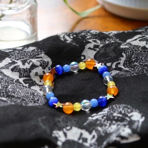 Aroace pride flag star beaded gemstone bracelet. The beads are the aroace flag colors (orange, yellow, white, blues) and holographic stars.