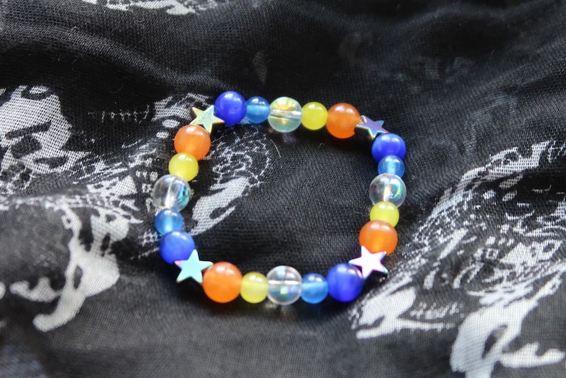 May include: A colorful beaded bracelet with blue, yellow, orange, and clear beads. The bracelet has silver star charms.
