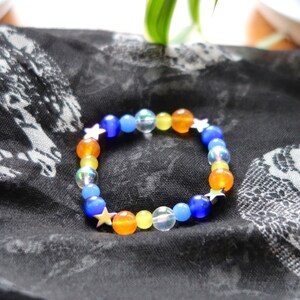 Aroace pride flag star beaded gemstone bracelet. The beads are the aroace flag colors (orange, yellow, white, blues) and holographic stars.
