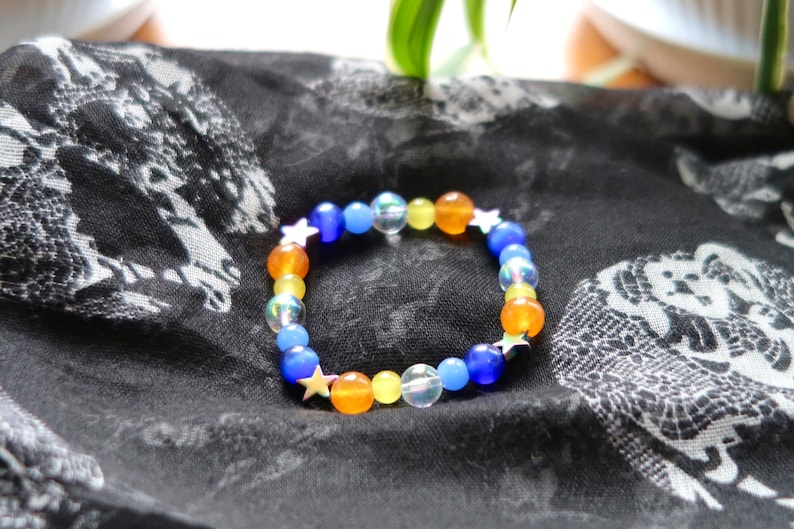 Aroace pride flag star beaded gemstone bracelet. The beads are the aroace flag colors (orange, yellow, white, blues) and holographic stars.