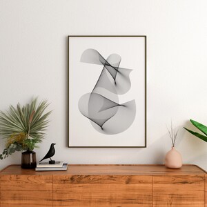 May include: A black and white abstract line art print in a brown frame hanging on a white wall above a wooden dresser with a black bird figurine, a vase with green leaves, and a pink vase with dried branches.