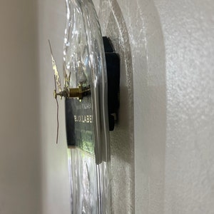 Puede incluir: Una botella de vidrio transparente con una etiqueta negra que dice "Johnnie Walker Black Label" se ha reutilizado como reloj de pared. Las manecillas del reloj son doradas y el mecanismo del reloj est&aacute; unido a la parte posterior de la botella.