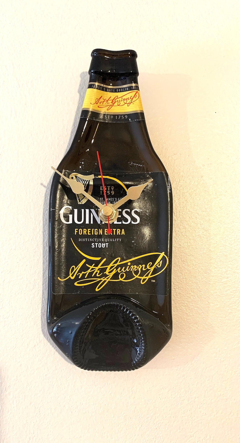 May include: A black Guinness beer bottle clock with gold hands and the text "ESTD 1759", "GUINNESS", "FOREIGN EXTRA", "DISTINCTIVE QUALITY STOUT", and "Arthur Guinness" in gold lettering.