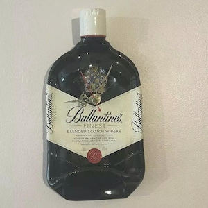 Reloj de pared con tapa y botella de whisky Ballantine aplastada/aplanada