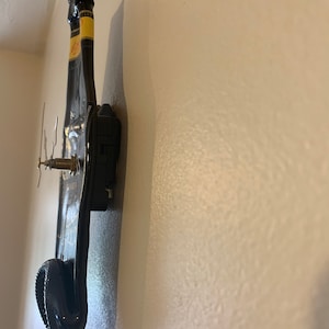May include: A black wine bottle clock mounted on a white wall. The clock hands are visible and the bottle is positioned vertically.