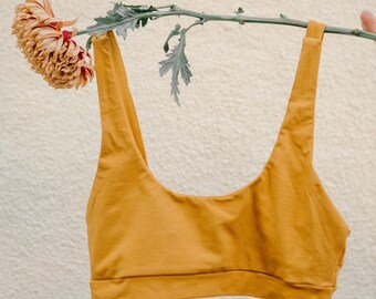 May include: A mustard yellow sports bra with a scoop neck and thin straps.