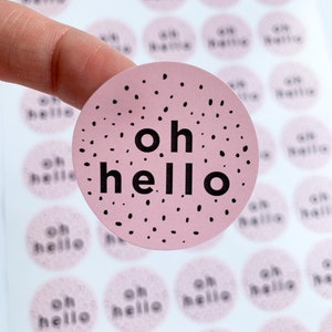 May include: A sheet of pink and white round stickers with the text "oh hello" in black lettering. The stickers have a black polka dot pattern.