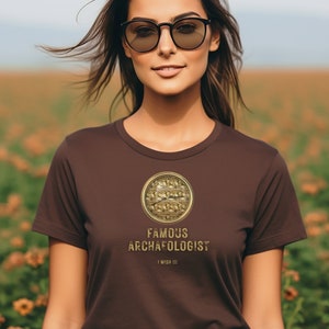 Peut inclure: T-shirt marron avec un graphique doré d'une boussole et le texte "Famous Archaeologist I Wish I I I".