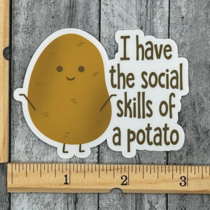 May include: A white sticker with a brown potato cartoon character with a smiling face and the text "I have the social skills of a potato".
