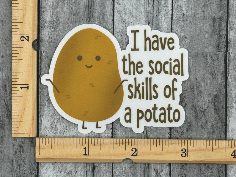 May include: A white sticker with a brown potato cartoon character with a smiling face and the text "I have the social skills of a potato".