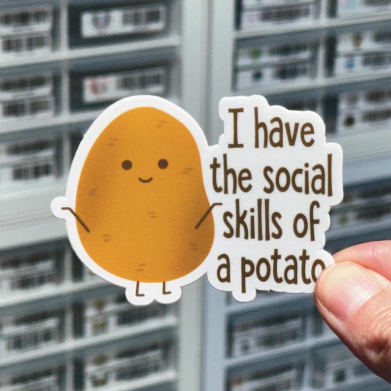 May include: A white sticker with a cartoon potato with a smiling face and the text "I have the social skills of a potato".