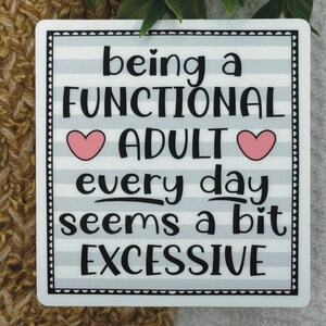 May include: A square sticker with a light blue and white horizontal striped background. The text reads: being a FUNCTIONAL ADULT every day seems a bit EXCESSIVE. Two small pink hearts are placed on either side of the word ADULT.