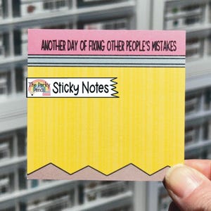May include: A square sticky note designed to look like a pencil, featuring a pink eraser top with the text 'ANOTHER DAY OF FIXING OTHER PEOPLE'S MISTAKES', a grey metal band, a yellow body, and a brown pointed tip at the bottom edge.
