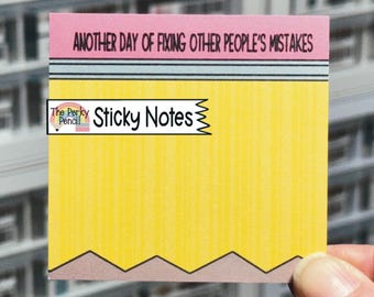 May include: A square sticky note designed to look like a pencil, featuring a pink eraser top with the text 'ANOTHER DAY OF FIXING OTHER PEOPLE'S MISTAKES', a grey metal band, a yellow body, and a brown pointed tip at the bottom edge.