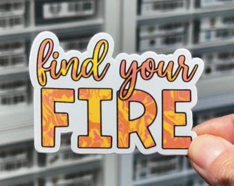May include: A die-cut sticker featuring the text find your FIRE in a two-line layout. The word find your is written in a cursive orange-to-pink gradient font, while the word FIRE is in a bold block font with a marbled orange and yellow pattern.