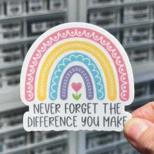 May include: A rainbow sticker with a heart in the center and the text "Never forget the difference you make".