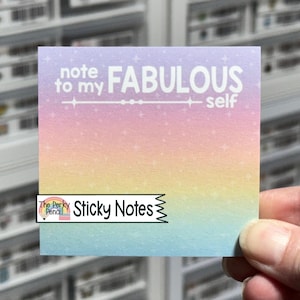May include: A square sticky note featuring a pastel rainbow gradient background with a subtle star pattern. The text "note to my FABULOUS self" is printed in white at the top, accompanied by a decorative horizontal line with small circular accents.