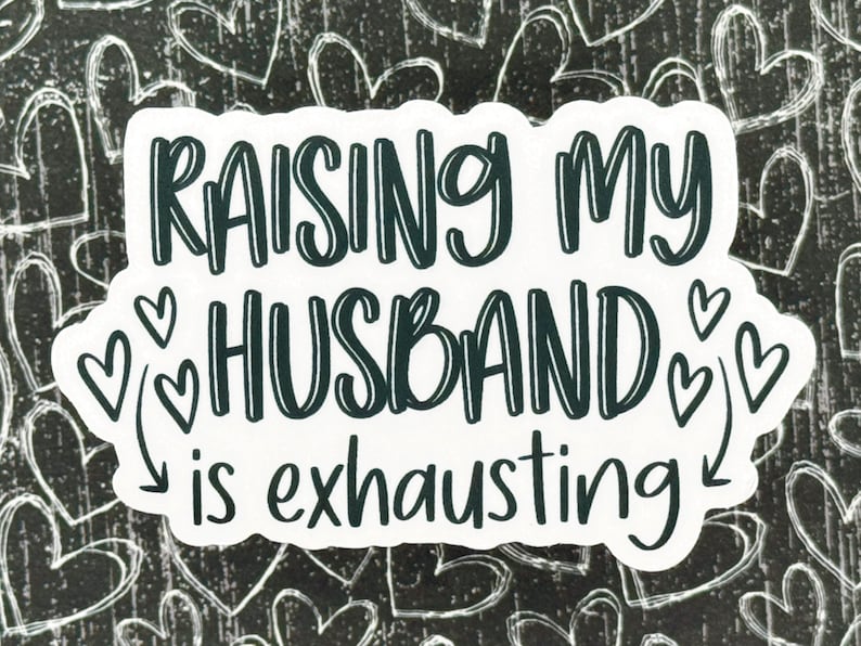 May include: White sticker with black text that reads "Raising my husband is exhausting" with hearts around the word "husband".