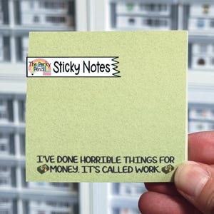 May include: A square light green sticky note featuring the text "I'VE DONE HORRIBLE THINGS FOR MONEY. IT'S CALLED WORK." with small illustrations of stacks of cash on either side. A white banner at the top displays "The Perky Pencil Sticky Notes."