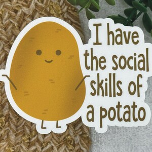 May include: A white sticker with a brown potato cartoon character with a smiling face and the text "I have the social skills of a potato".