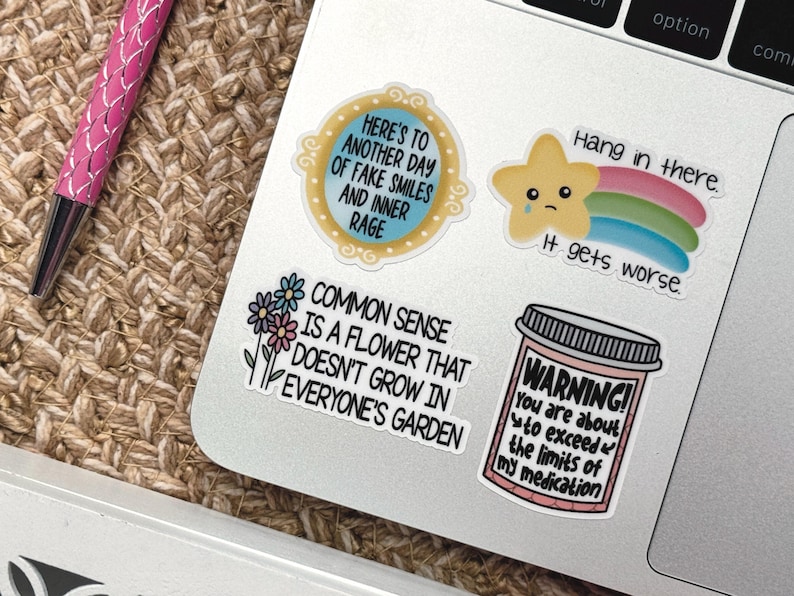 May include: A set of five stickers with humorous sayings. The stickers are printed on white paper with black text. The stickers feature a mirror with the text "Here's to another day of fake smiles and inner rage", a star with a rainbow and the text "Hang in there. It gets worse", a flower with the text "Common sense is a flower that doesn't grow in everyone's garden", and a pill bottle with the text "Warning! You are about to exceed the limits of my medication".