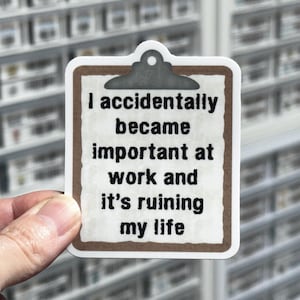 May include: A sticker in the shape of a clipboard with the text "I accidentally became important at work and it's ruining my life." The sticker has a brown border and a white background.