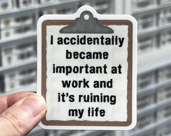 May include: A sticker in the shape of a clipboard with the text "I accidentally became important at work and it's ruining my life." The sticker has a brown border and a white background.